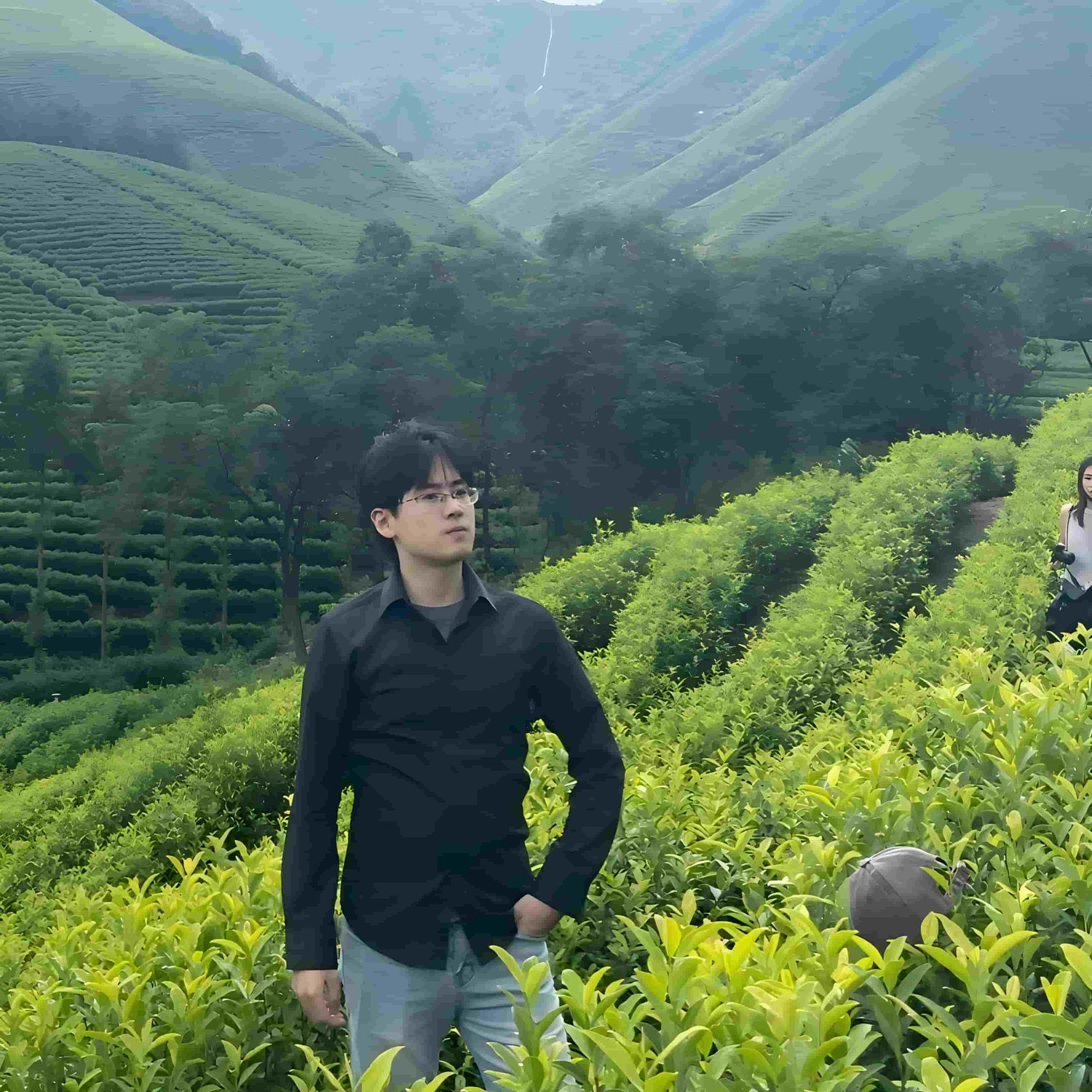 SootheHerbs creative partner Shawn Brown standing thoughtfully amidst a vibrant green tea plantation hills, bringing a nature-inspired vision to life.